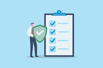 Businessman holding a shield with a checkmark in front of a completed checklist on a clipboard