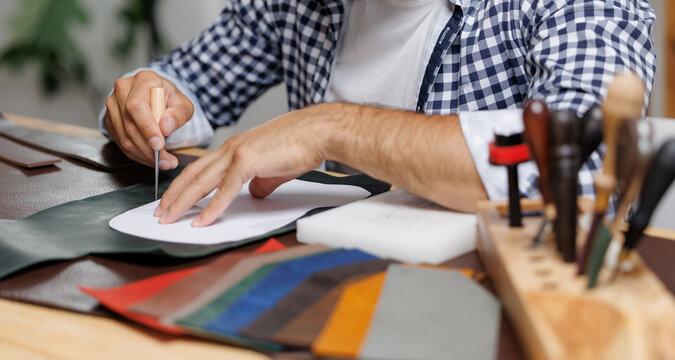 Male craftsman cutting leather patterns in workshop, workplace of hand made worker