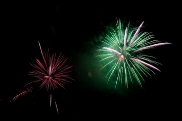 Red and green fireworks explode in the night sky celebration