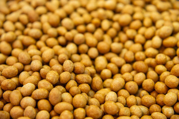 Close-up of delicious peanuts roasted in coconut glaze. Many are lying on the plane