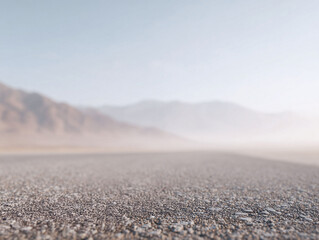 Serene desert highway receding into the distant mountains under a clear, hazy sky. Evokes travel, journeys, freedom, and adventure. Ideal for travel blogs or web banners.