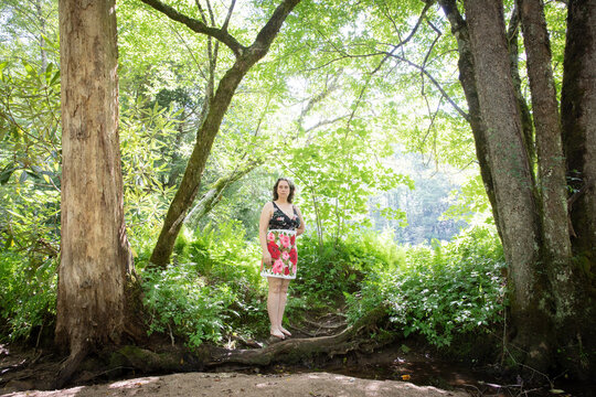 woman in bathing suit and floral towel by creek in woods