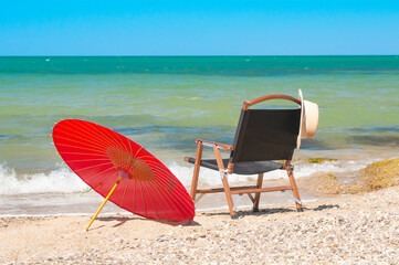 Red chinese parasol and chair on a seashore at sunny day