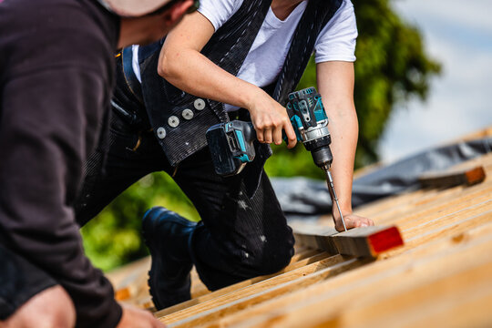 Dachdecker mit akkubohrer auf dach