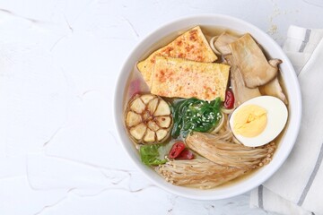 Tasty ramen with enoki and king oyster (eryngii) mushrooms on white table, top view. Space for text