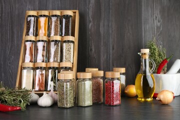 Different spices and glass jars on grey wooden table
