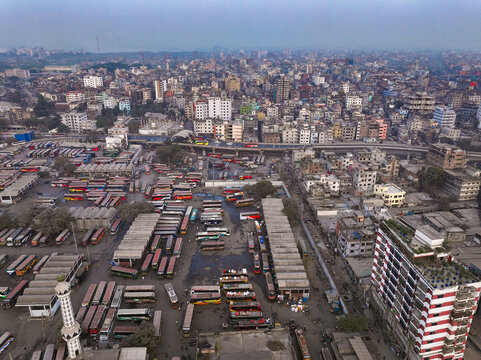 Aerial view of a bustling bus terminal filled with rows of colorful buses contrasting with the dense urban sprawl, Sayedabad Bus Terminal, Dhaka, Dhaka Division, Bangladesh.