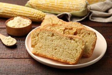 Freshly baked cornbread, cobs and flour on wooden table, closeup