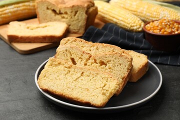 Freshly baked cornbread, cobs and seeds on black table, closeup