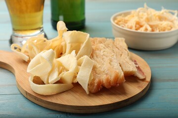 Dried squid snacks and beer on light blue wooden table, closeup