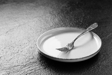 Fork and white plate on dark surface, minimalistic design, elegant dining setup for modern kitchens