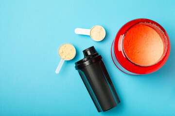 Protein shake with protein powder on a colored background. The powder is mixed with water or milk....