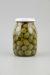 Green olives in a glass jar on a white background, isolated