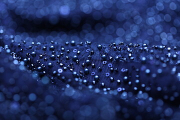 Detailed close-up of pearl navy blue lace with sequins and beads on delicate mesh, creating a shimmering texture perfect for fashion, couture, and luxury fabric backgrounds