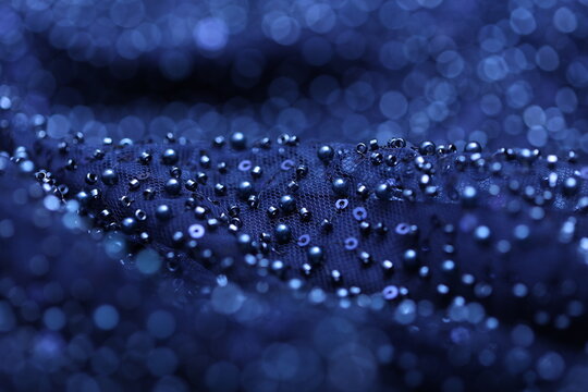 Detailed close-up of pearl navy blue lace with sequins and beads on delicate mesh, creating a shimmering texture perfect for fashion, couture, and luxury fabric backgrounds
