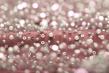 Detailed close-up of pearl pink lace with sequins and beads on delicate mesh, creating a shimmering texture perfect for fashion, couture, and luxury fabric backgrounds