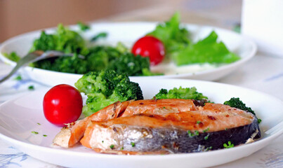 A plate of salmon, broccoli, and tomato - A Balanced Dinner Plate with the Red Cherry Tomato in Focus