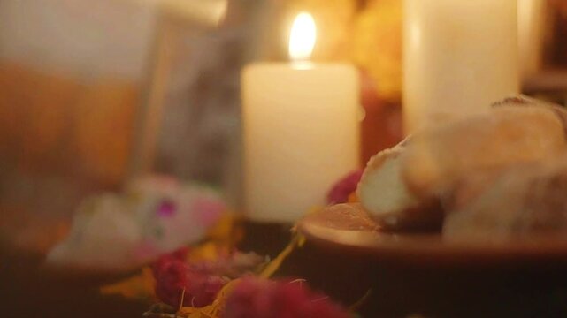 Una vela encendida en una ofrenda de D&iacute;a de Muertos con calaveritas de az&uacute;car.