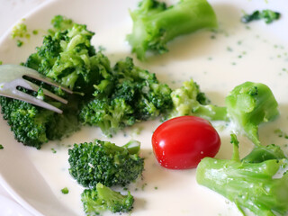 A Fork Taking a Piece of Broccoli from a Plate with a Creamy Sauce