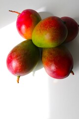 Beautiful and original composition with delicious ripe and tropical mangoes. Healthy and organic food concept. Photo with a white background and hard shadows. With space for text.