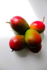 Fototapeta premium Beautiful and original composition with delicious ripe and tropical mangoes. Healthy and organic food concept. Photo with a white background and hard shadows. With space for text.