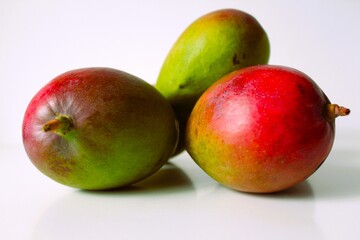 Beautiful and original composition with delicious ripe and tropical mangoes. Healthy and organic food concept. Photo with a white background and hard shadows. With space for text.