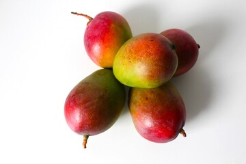 Beautiful and original composition with delicious ripe and tropical mangoes. Healthy and organic food concept. Photo with a white background and hard shadows. With space for text.