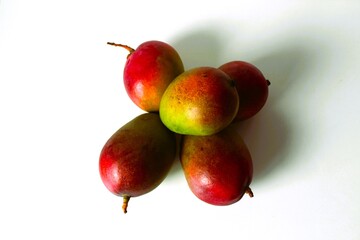 Beautiful and original composition with delicious ripe and tropical mangoes. Healthy and organic food concept. Photo with a white background and hard shadows. With space for text.