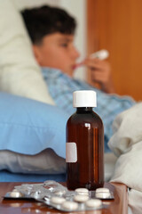 taking your temperature with the thermometer and the medicines on the bedside table