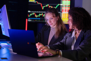 Colleagues discuss stock market trends in a modern office setting during evening hours