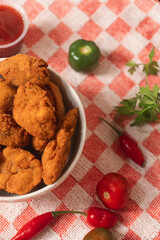 Close-up view of a bowl of nuggets surrounded by vegetables and sauces.