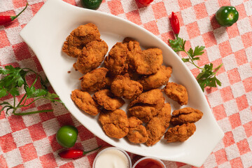 Bird's-eye view of fried chicken with vegetables and sauces around it.