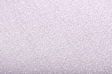 Close-up of elegant, off-white pearl lace fabric with delicate beads and sequins on fine mesh, creating a shimmering texture ideal for fashion, bridal, and luxury design concepts.