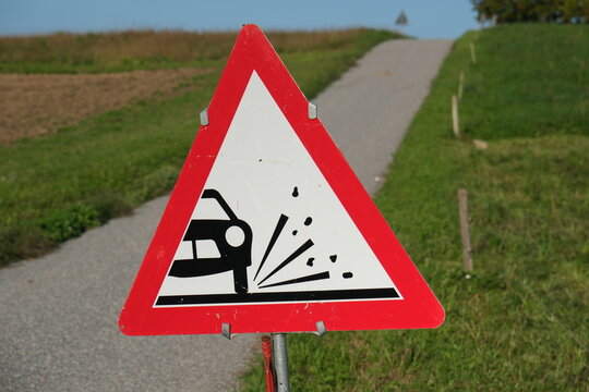 Verkehrszeichen Vorsicht Rollsplitt, Schotter auf der neu ausgebesserten Fahrbahn auf dem Lande, Unfallgefahr durch beeintr&auml;chtigte Haftung vom Fahrzeug