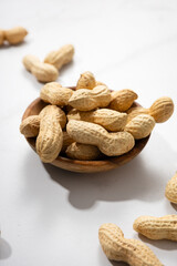 Close up of  peanuts in bowl on light surface