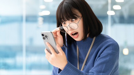 スマートフォンの画面を見て驚く女性