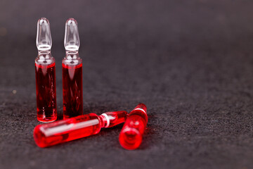Red B12 glass ampoules stand out on black background showing nutrition therapy and health support in elegant style.