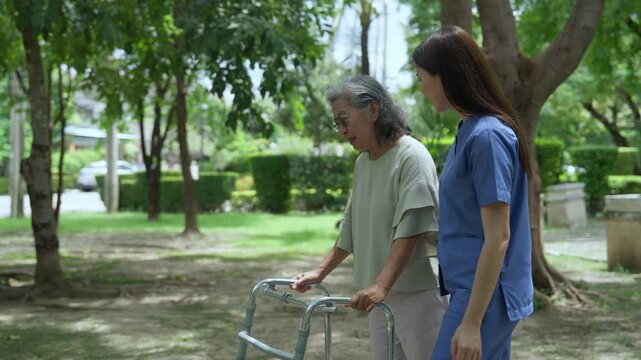 The caregiver is helping an elderly Asian woman rehabilitate her walking and monitor her condition after she underwent knee surgery, using treatment information from her doctor.