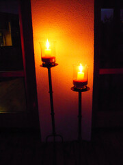 Two lit candles on candlesticks in the evening