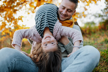 Father and young girl on walk in autumn nature, having fun.