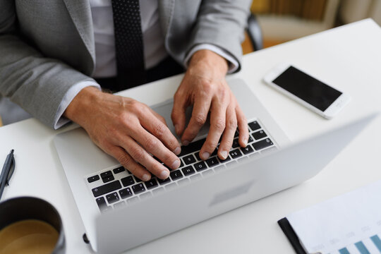 Close up of businessman working on laptop in office.