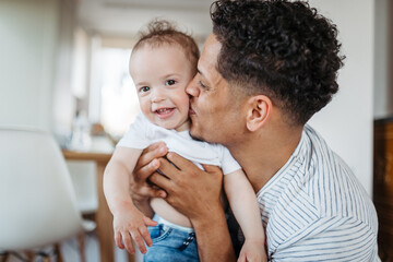 Father and small toddler son. Dad hodling and kissing boy.