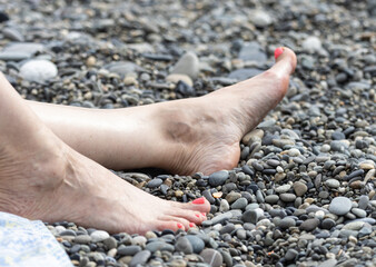 A woman's feet are laying on a rocky beach