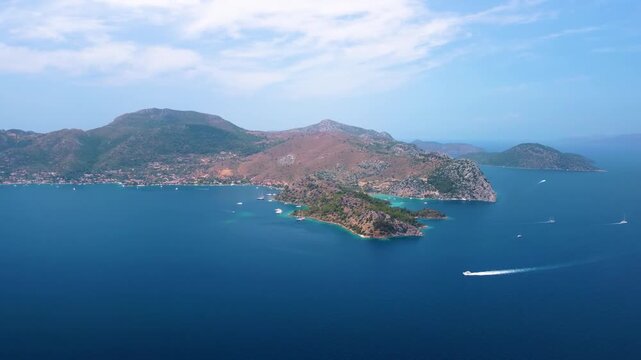 An idyllic aerial view captures the beauty of Cennet Koyu, or Paradise Bay, in Turkey. Crystal clear turquoise waters meet lush green hills and a pristine coastline, dotted with boats enjoying the tra