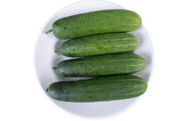 Fresh cucumbers gleam on white plate, looking crisp and ready to eat. vibrant green hues promise healthy and delicious meal