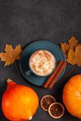 Pumpkin spice latte with cinnamon and autumn leaves. Copy space