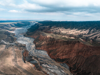 Vibrant Red-Brown Mountains and Winding River Channels of Anjihai Grand Canyon, Xinjiang, China - Aerial View​