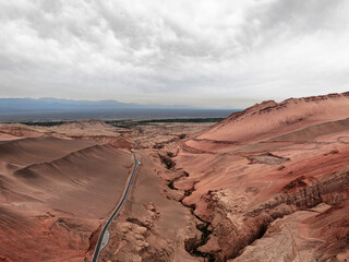 A desert highway curves through the dramatic landscape of Anjihai Grand Canyon (Red Mountain Canyon), Xinjiang, China.​