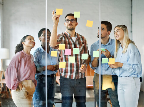 Business people meeting at office and using sticky notes on glass to share idea. Brainstorming and teamwork concept. Sticky note on glass wall.