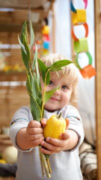 Child holding etrog and lulav, Sukkot celebration, Jewish holiday tradition, autumn festival, ritual blessing, cultural heritage, harvest season, sacred custom, spiritual symbol